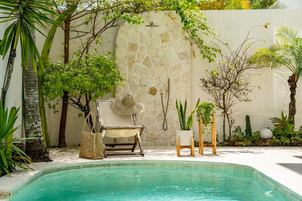 Tropische tuin met zwembad, exotische planten en een ligstoel vol zomerse relax vibes.
