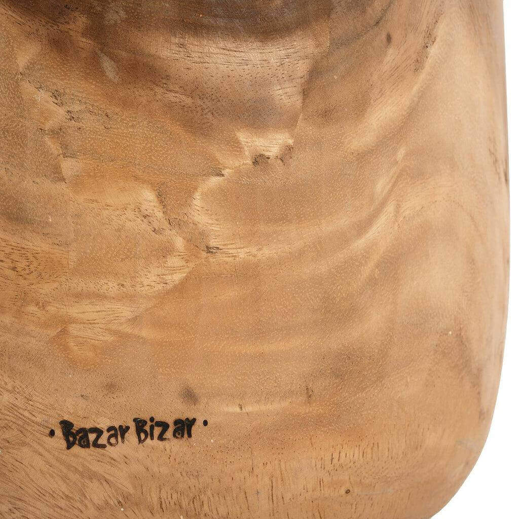 Close-up van de natuurlijke houtstructuur van een De Aukai kruk, gemaakt van suarhout met uniek 'Bazar Bizar' logo.