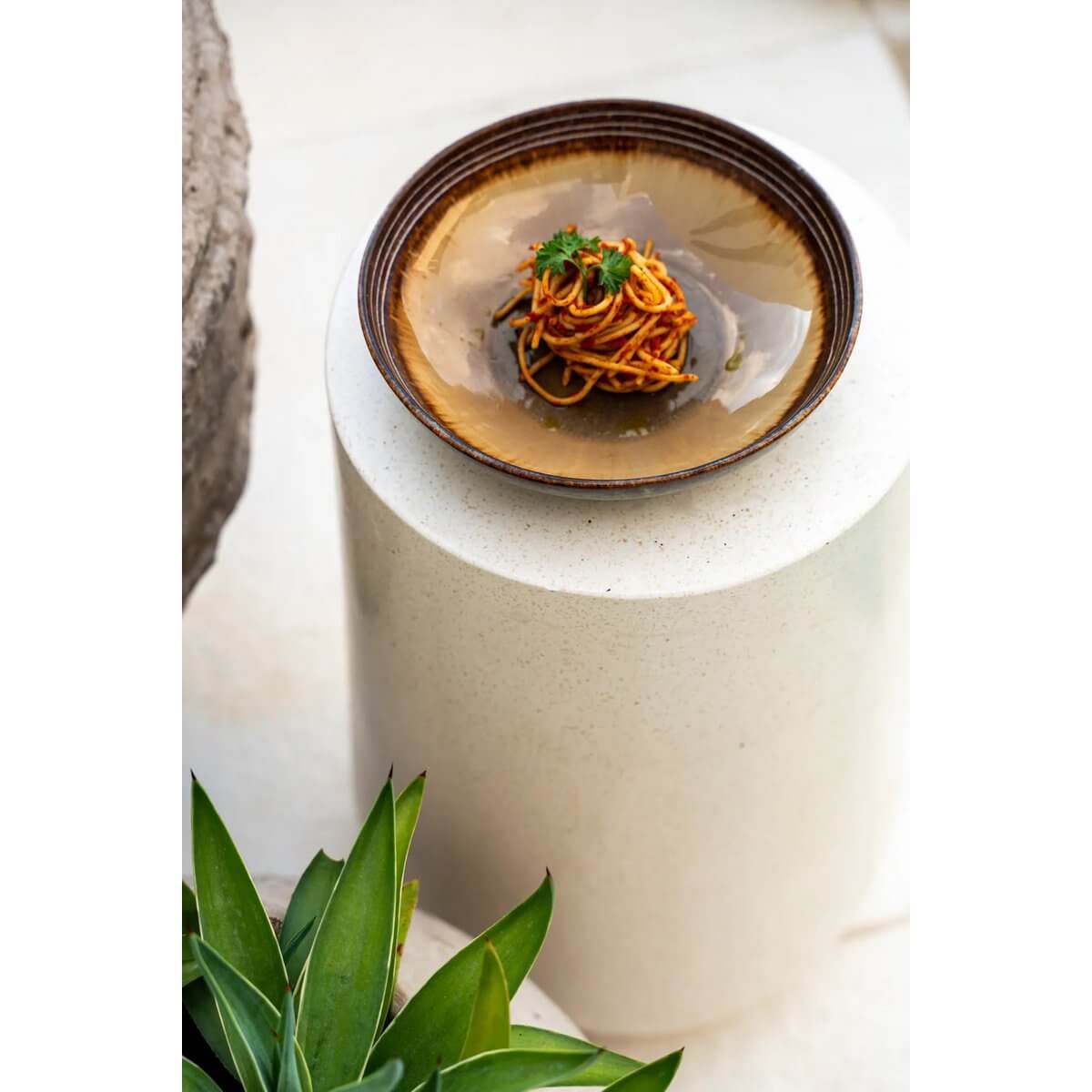 De Comporta Pastabord met portie pasta op stijlvolle tafel, handgemaakt Portugees keramiek met variërende kleurschakeringen.