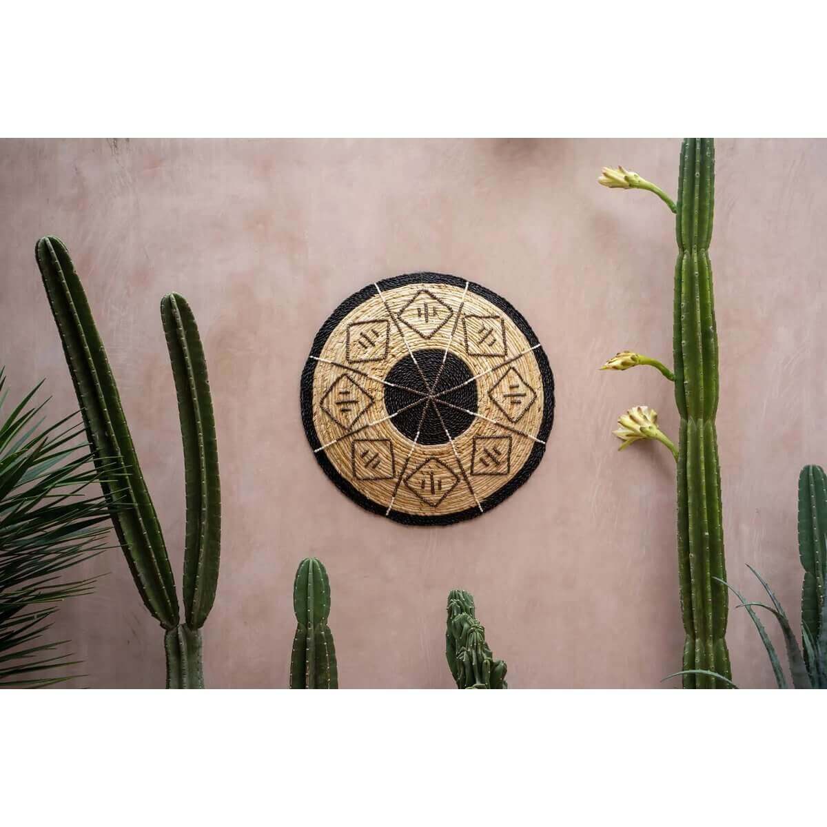 Uniek handgeweven decoratief bord met zwarte grafische details aan muur met cactussen, Bazar Bizar Living stijl.