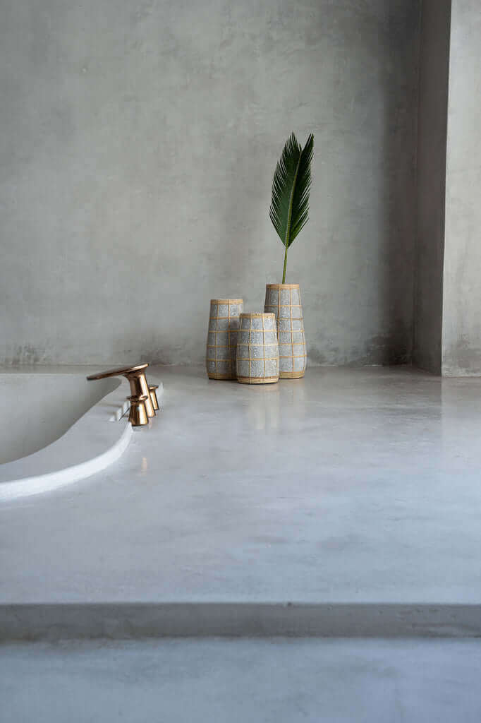 Stijlvolle terracotta vaas met rotan detail, geschikt voor droge bloemen, in een moderne badkamer setting.