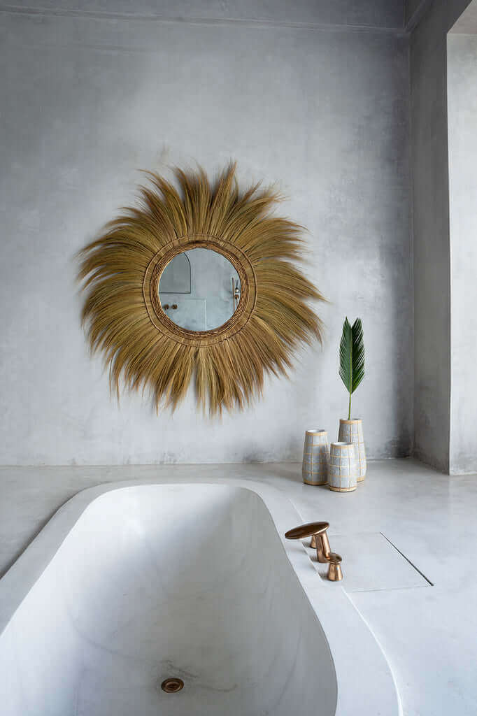 Stijlvolle badkamer met een zonnespiegel, strakke wastafel en decoratieve vazen voor een rustieke sfeer.
