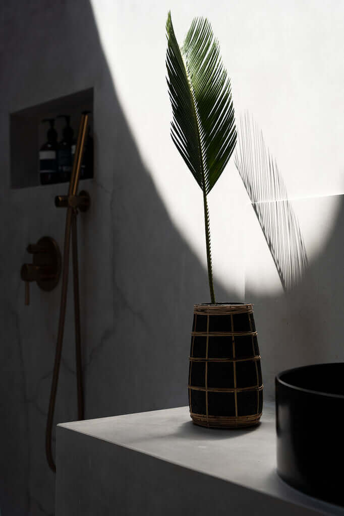 Slanke terracotta vaas met rotan detail, zwart naturel, 22 cm hoog. Niet-waterdicht, ideaal voor gedroogde bloemen, in zonverlichte badkamer.