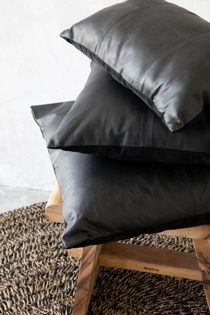 Elegant zwarte lederen kussenhoes op houten stoel, perfect voor moderne woonkamers.
