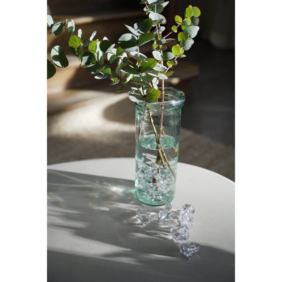 Bohemian De Jiandan Vaas in blauw, gemaakt van gerecycled glas, met minimalistisch ontwerp en groene takken op witte tafel.