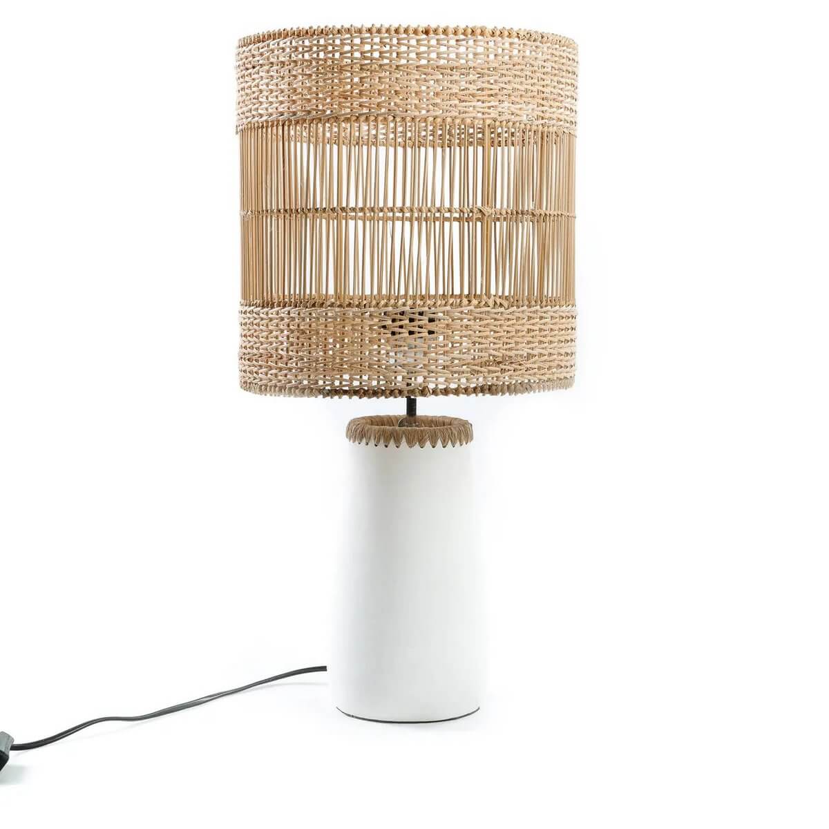 Bohemian style Kiska table lamp with white terracotta base and raffia-trimmed rattan shade, adding cozy light patterns.