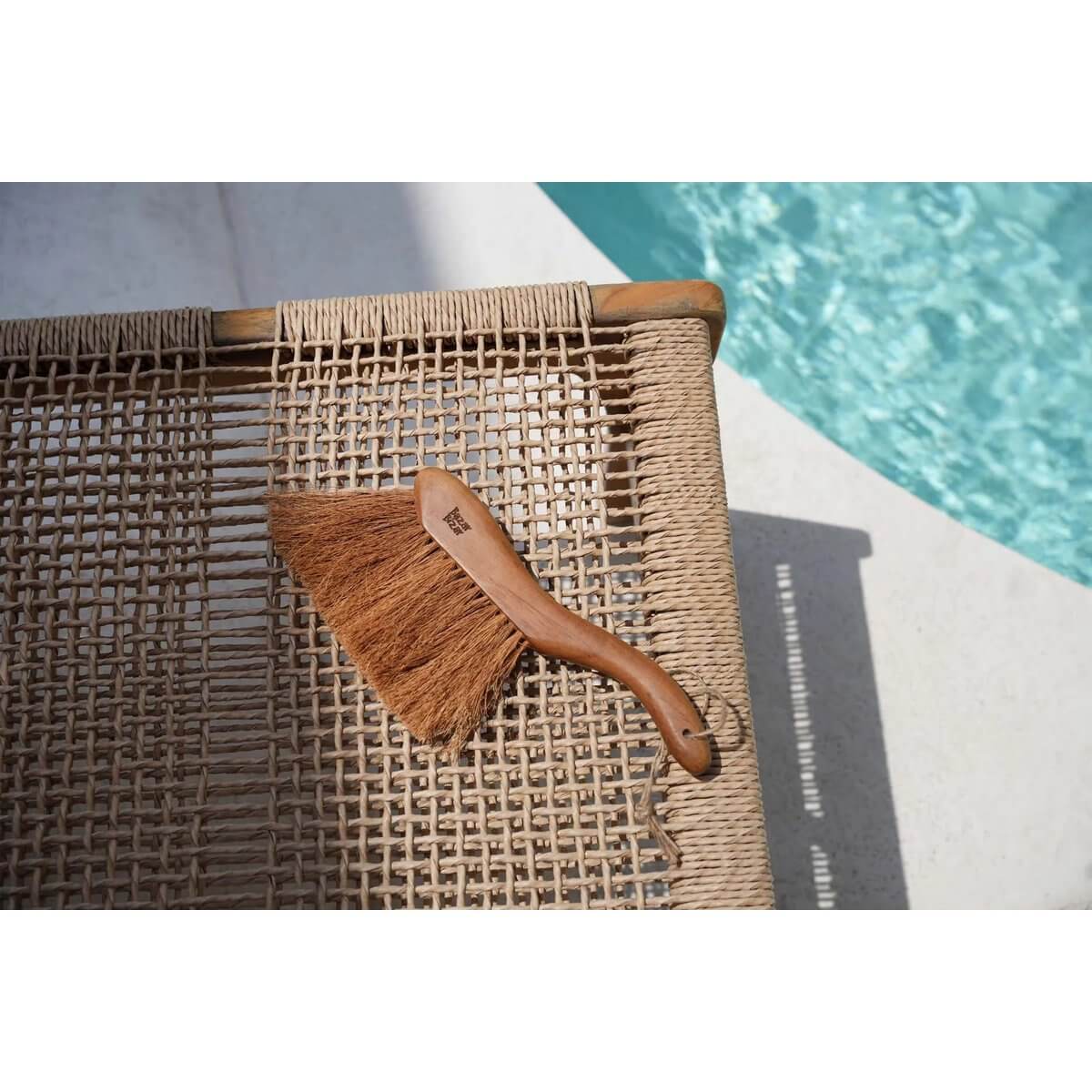 Bohemian style Maha Brush made of sustainable teak on woven surface near pool, perfect for a clean and elegant kitchen.