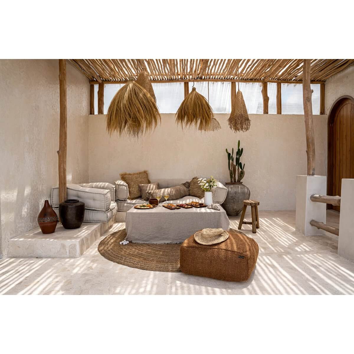 Bohemian-style patio with woven furniture, rustic decor, and natural lighting, featuring a straw hat perfect for a beach day.
