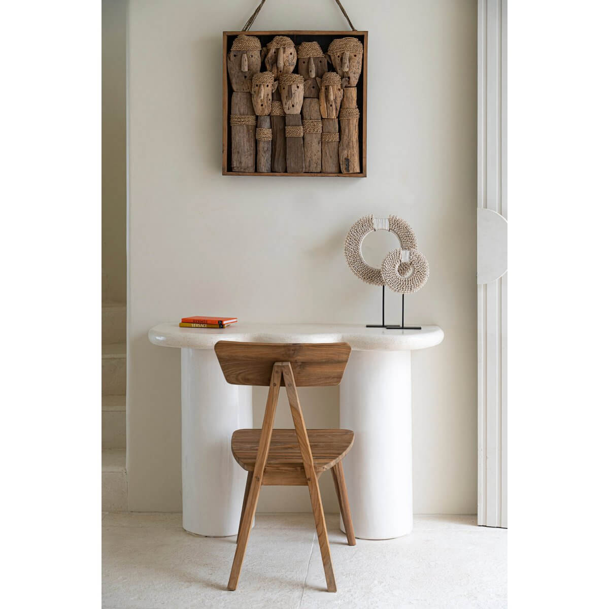 Bohemian-style room with shell disc decor on stand, wooden chair, and rustic wall art. Perfect coastal elegance.