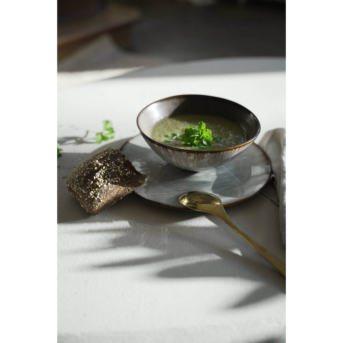 Peniche Cereal Bowl with soup, set on a stoneware plate, golden spoon and bread, inspired by the Portuguese coast style.