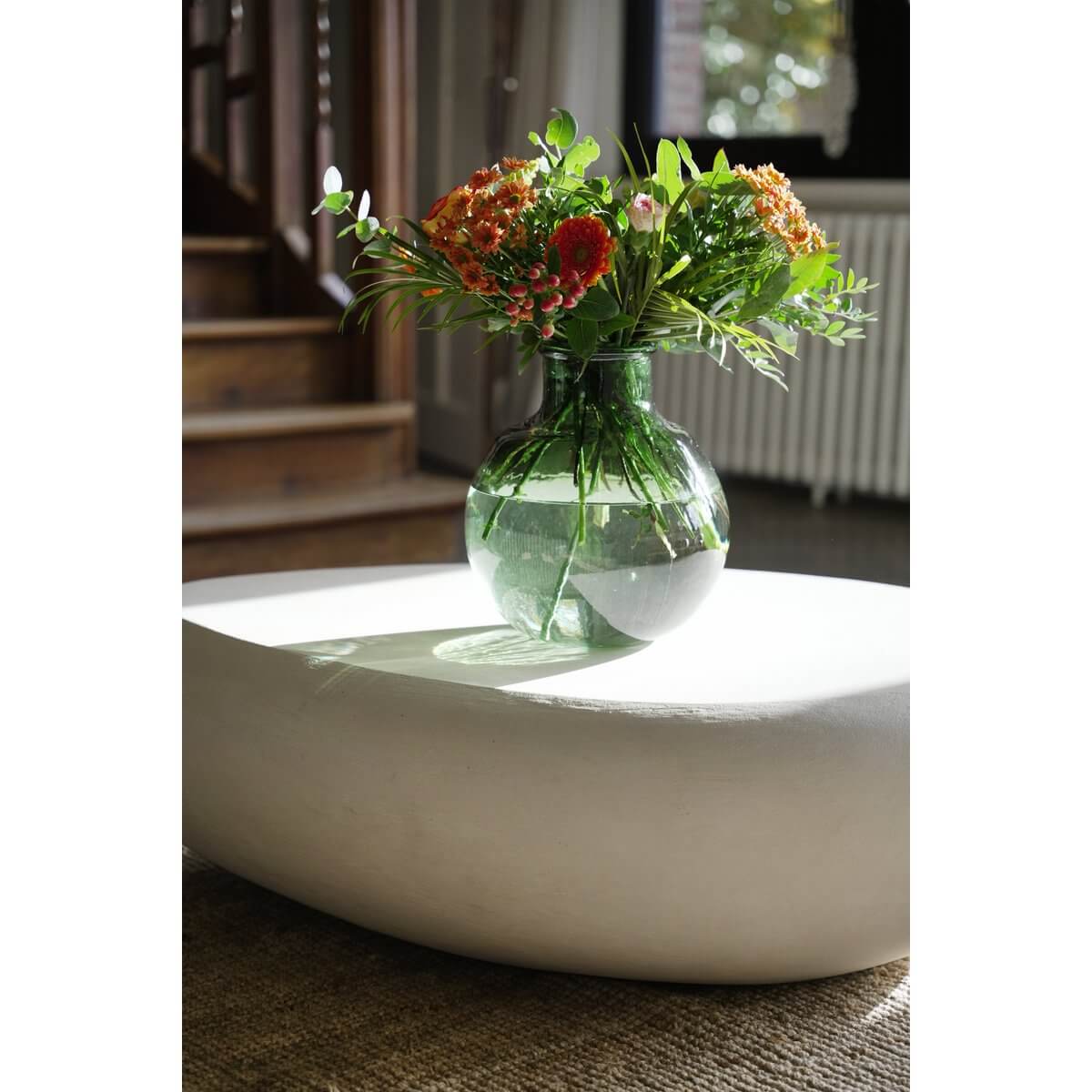 Bohemian style green De Qiezi Vaas displaying vibrant flowers, made from recycled glass, adding modern elegance to a room.