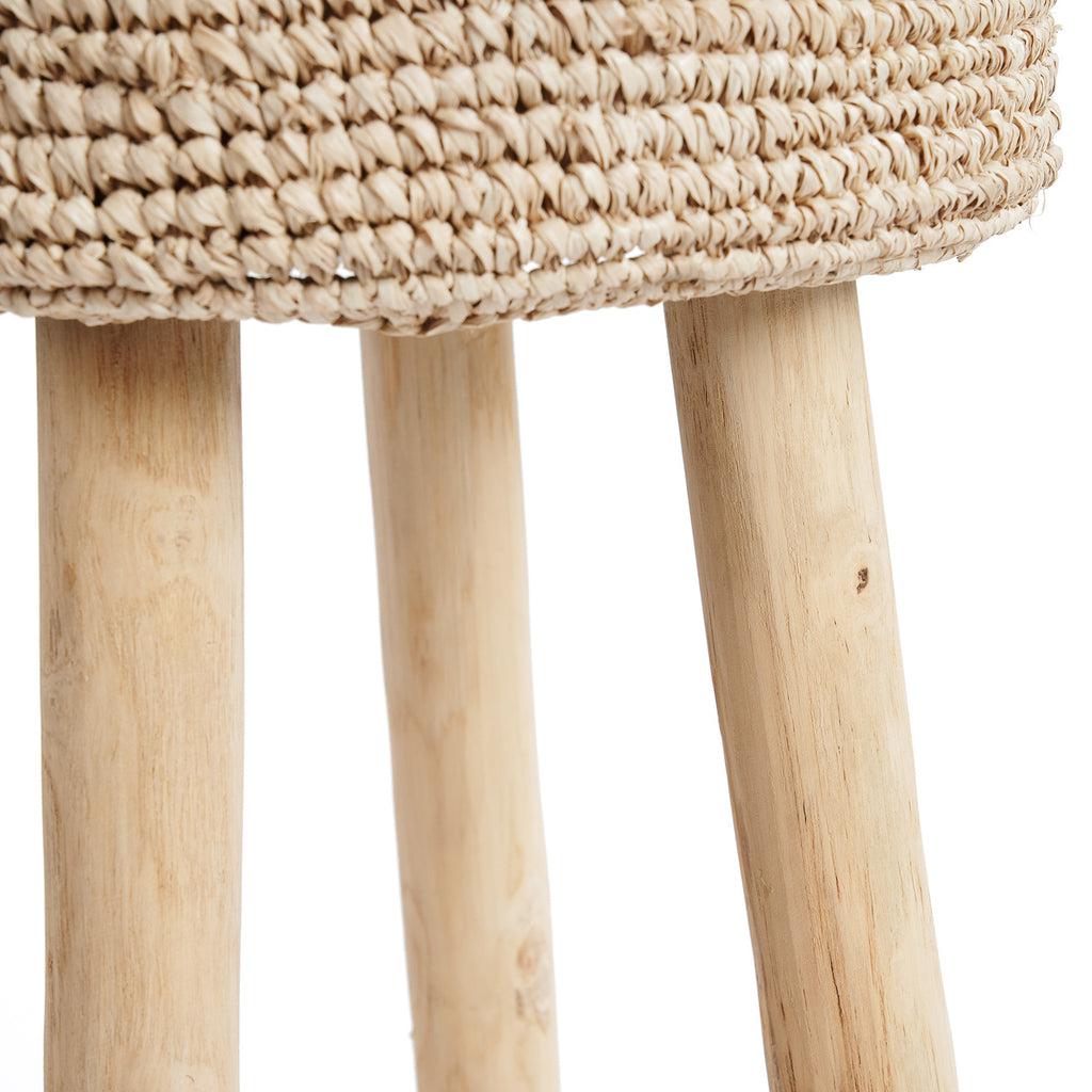 De Raffia barkruk met handgeweven raffia zitting en massief teakhouten poten, straalt natuurlijke elegantie en bohemian charme uit.