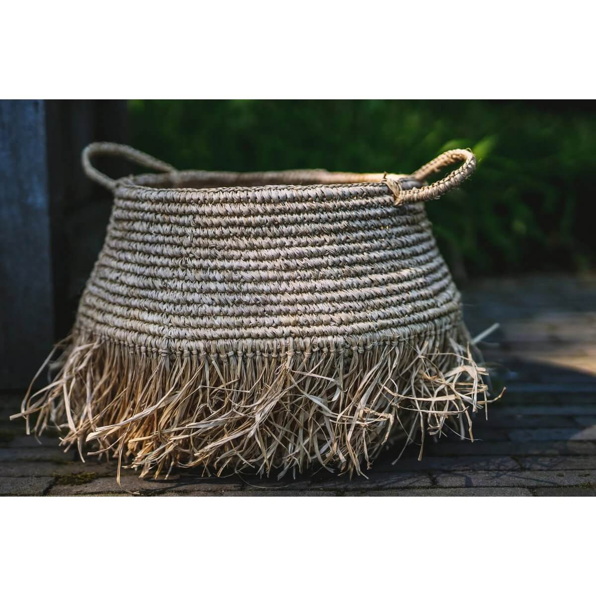 Bohemien raffia mand met speelse franjes, ideaal voor opslag of decoratie binnen en buiten.