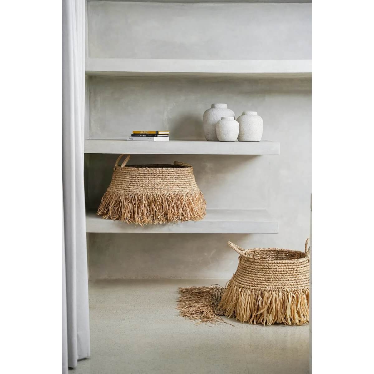 Bohemian raffia basket with playful fringe, perfect for stylish storage or decor, adding a natural touch to indoor and outdoor spaces.