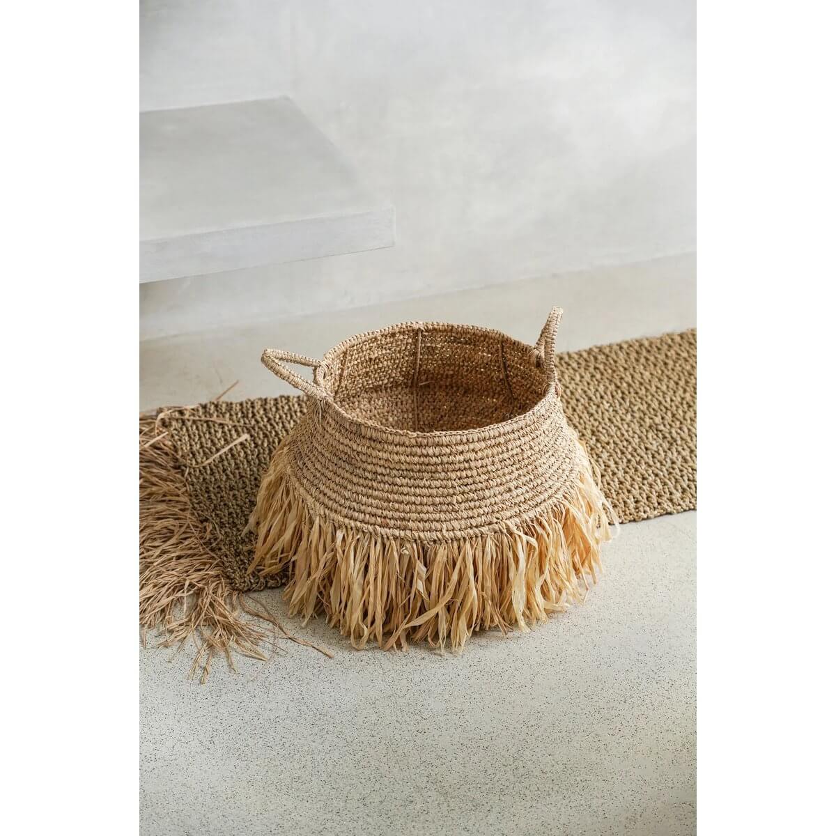 Bohemian raffia basket with fringe, perfect for storage and decor, adds tropical flair to indoor and outdoor spaces.