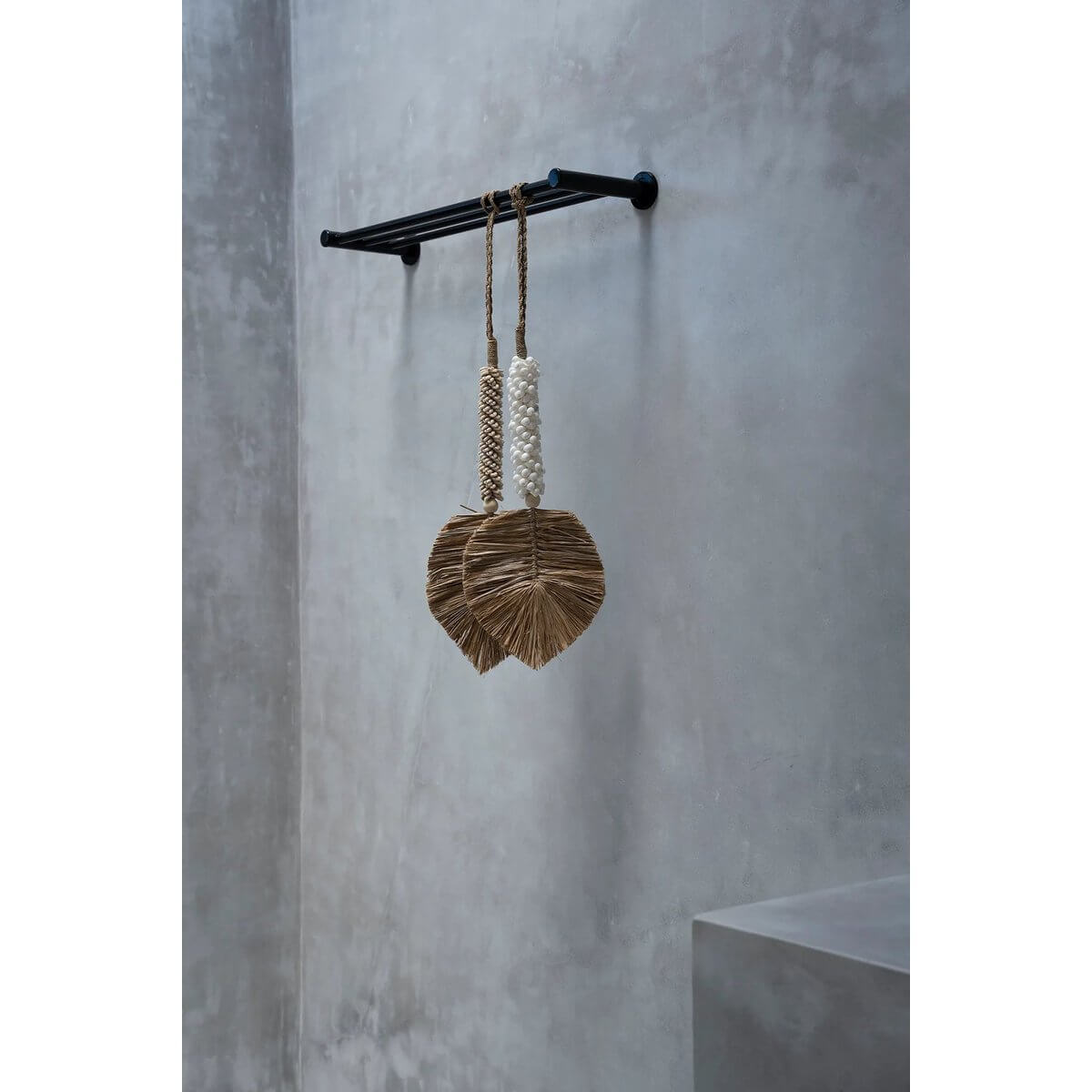 Bohemian raffia and shell tassel hanging on the wall, crafted by Balinese artisans for a coastal, exotic vibe. Elegant white and beige design.