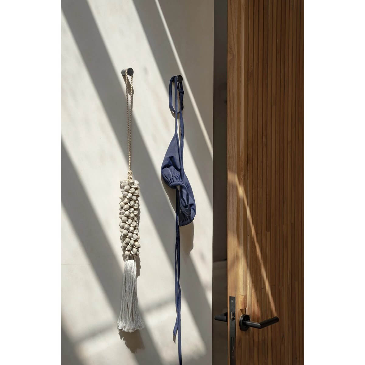 Gray De Shell & Cotton Kwastje hanging on door, adds bohemian charm to decor with handcrafted Balinese shells; unique piece by Bazar Bizar Living.