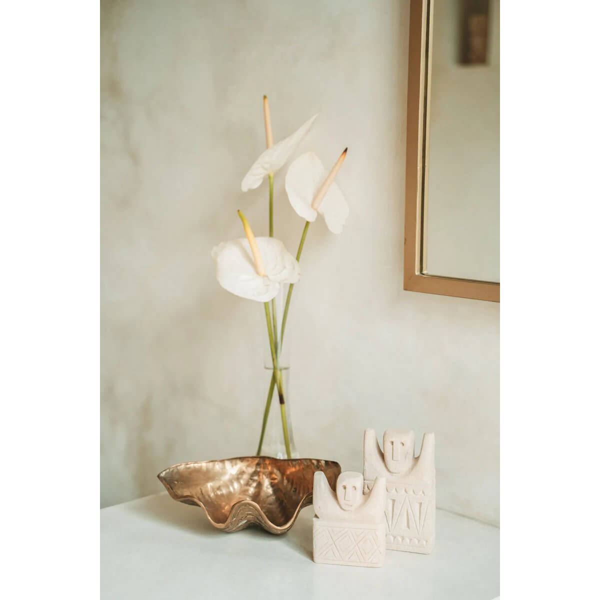 Bohemian Sumba stone sculptures #17 with a hand-sculpted design beside a metallic dish and white flowers in a serene setting.