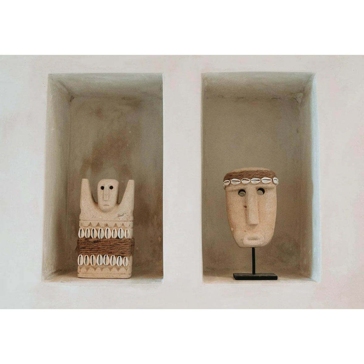 Twee handgesneden Sumba-steen beelden uit Indonesië, gemaakt van zandsteen en geplaatst in nissen voor bescherming en genezing.