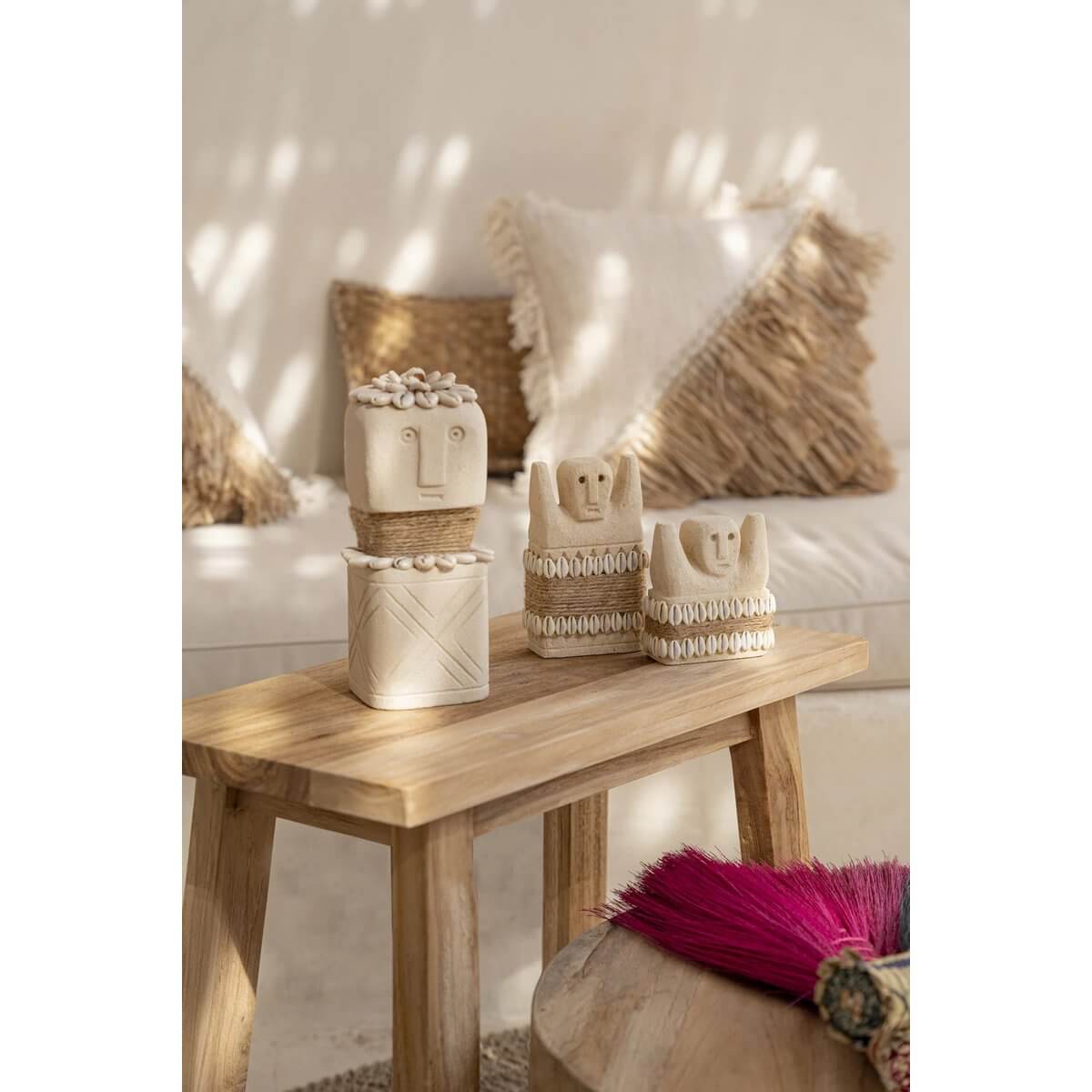 Bohemian Sumba stone statues on rustic table with cozy decor, showcasing unique handmade artistry from Indonesia.