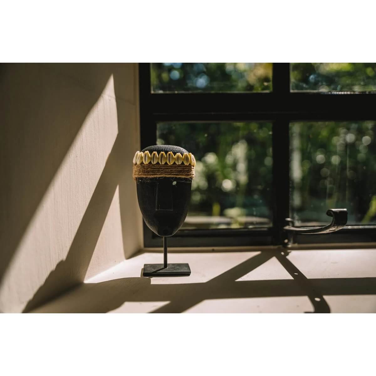 Bohemian Sumba-stone sculpture on a stand by a sunlit window, handmade from sandstone in Indonesia, perfect for home decor.