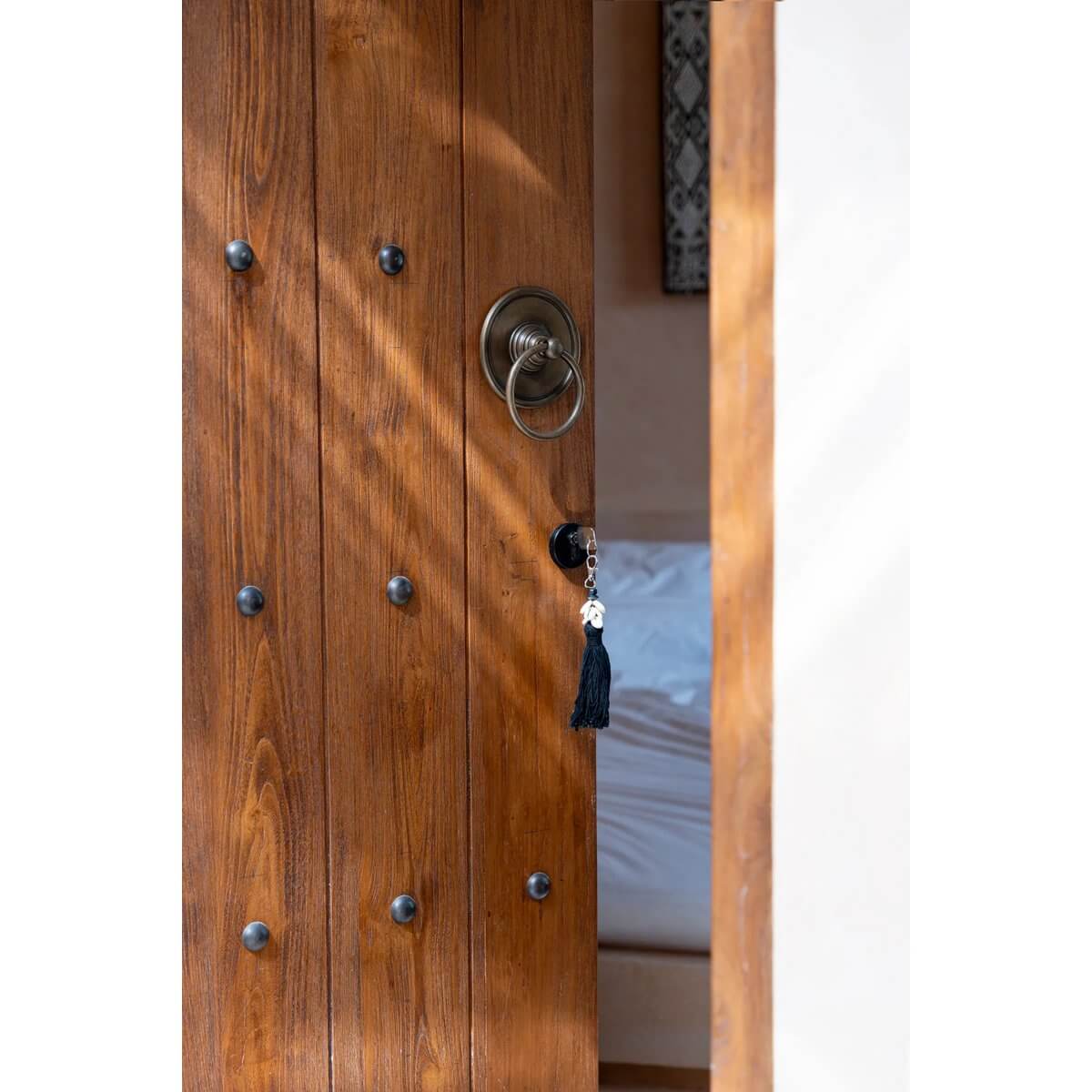 De Sumbawa Bohemian sleutelbos aan houten deurknop, zwartbruine kleur voor stijlvolle organisatie en rustieke charme.