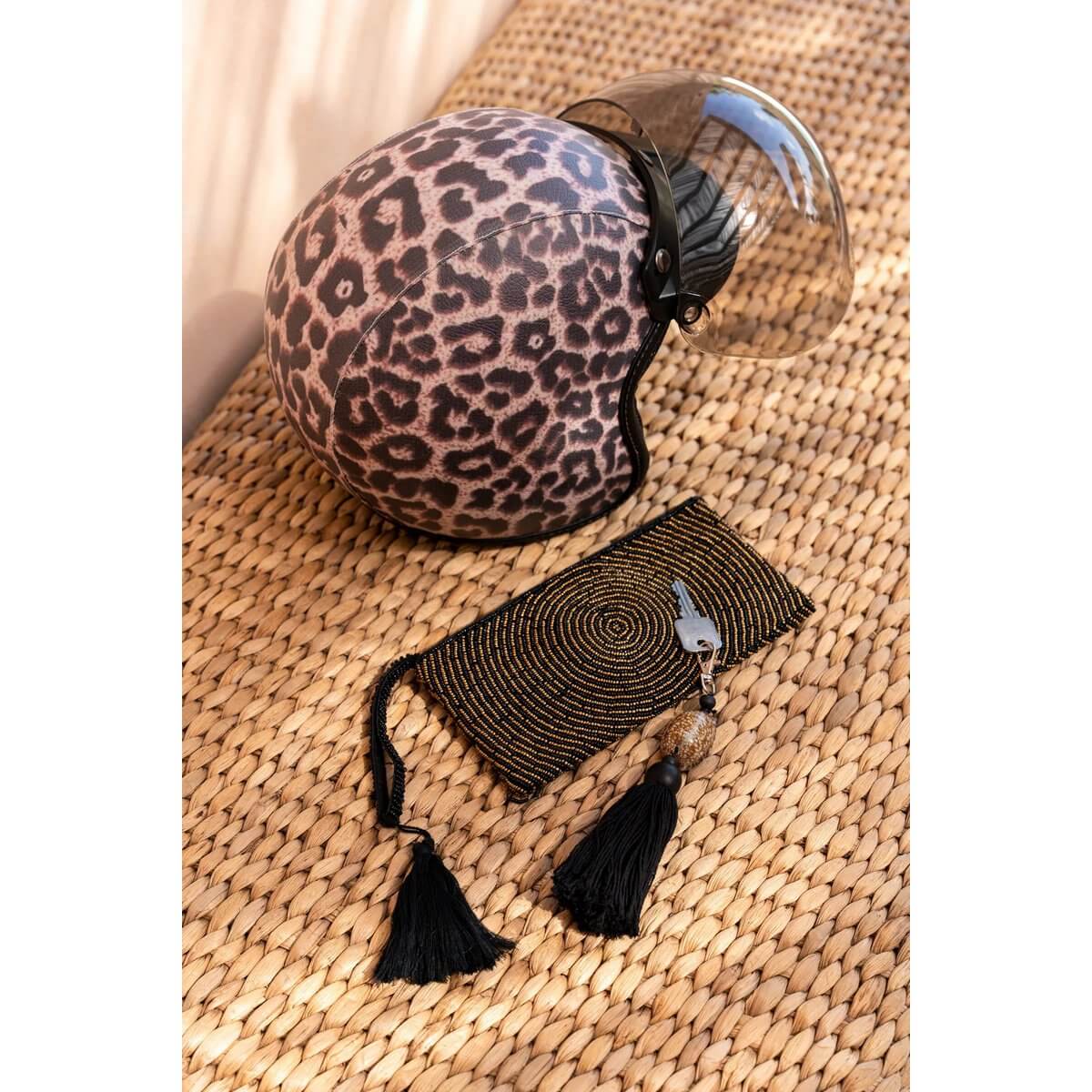 Bohemian black tassel keychain and matching patterned motorcycle helmet on wicker surface.