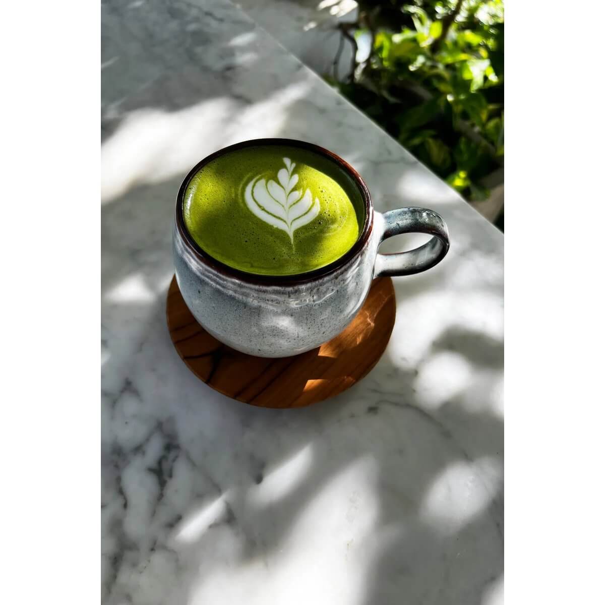 Cozy matcha latte in a mug on a stylish De Teak Root Nordic Coaster, adding a bohemian touch to a marble table setting.