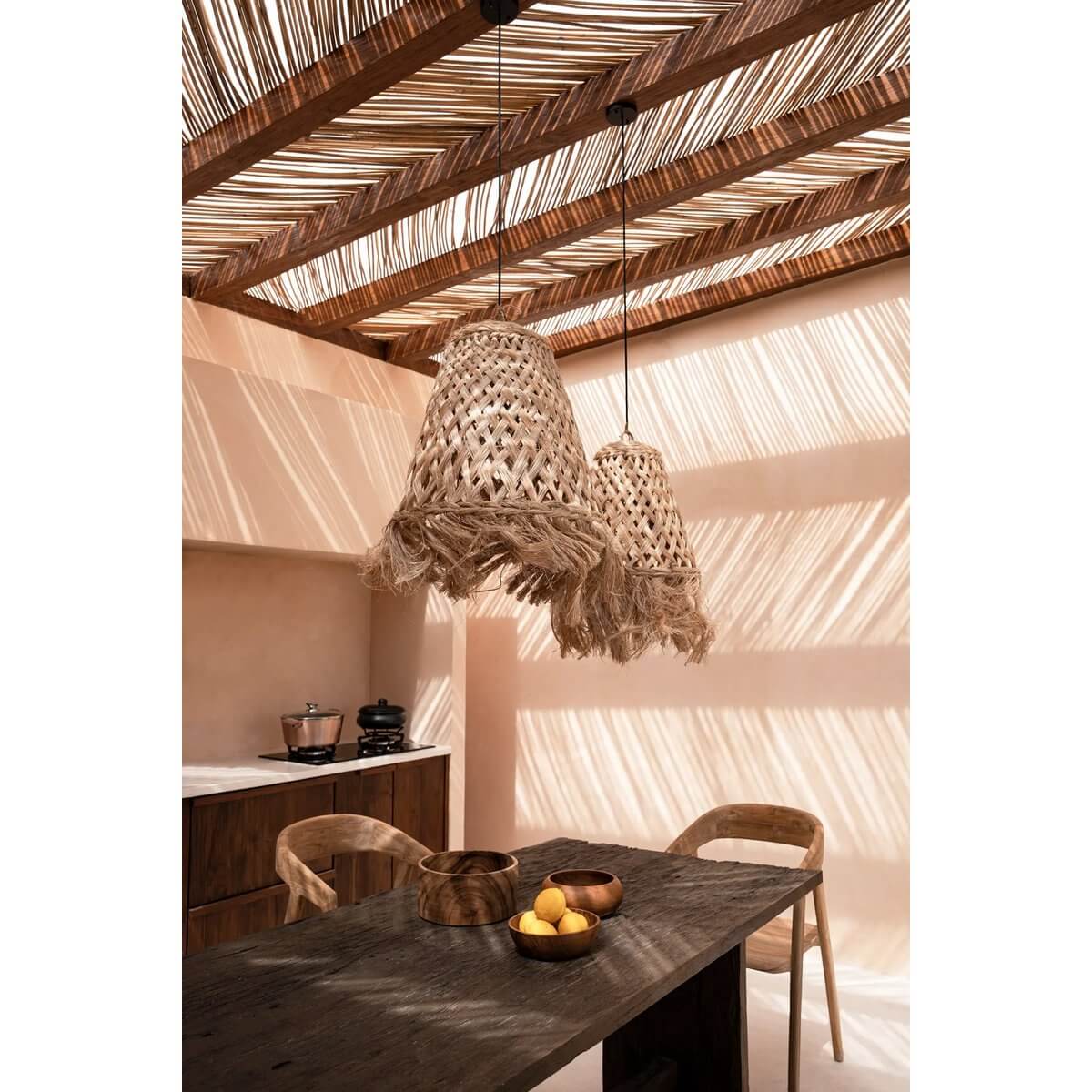 Bohemian style kitchen with teak root snack bowl on table, woven pendant lights, and natural wooden decor casting shadows.