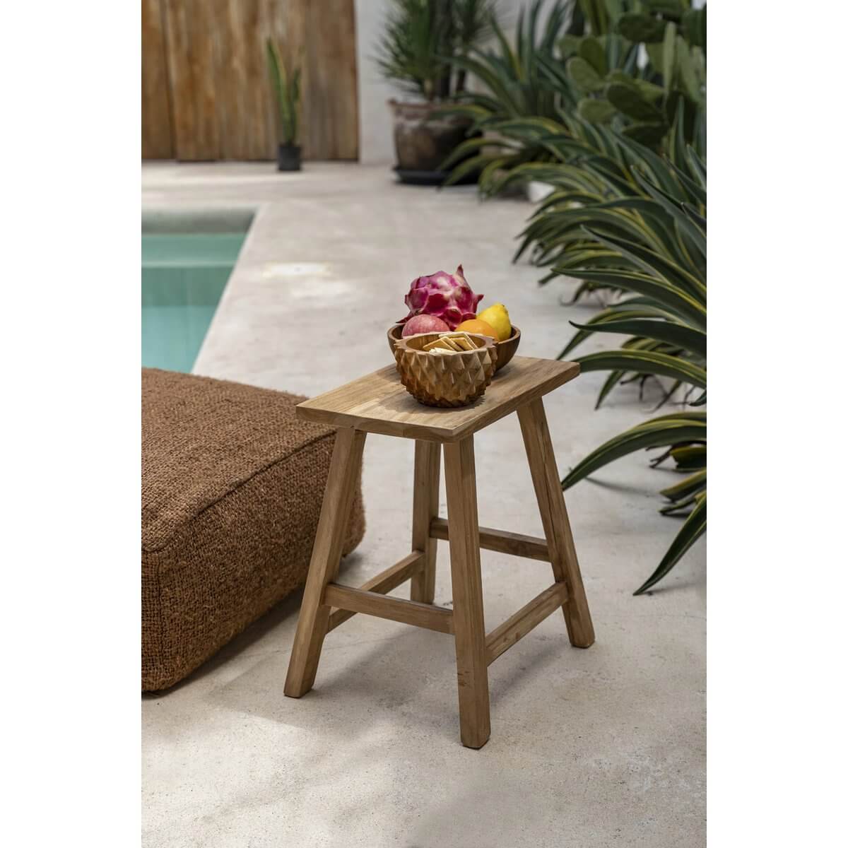 Bohemian De Teakwortel Durian Bowl on teak stool, filled with tropical fruits by the poolside, showcasing its unique textured design.
