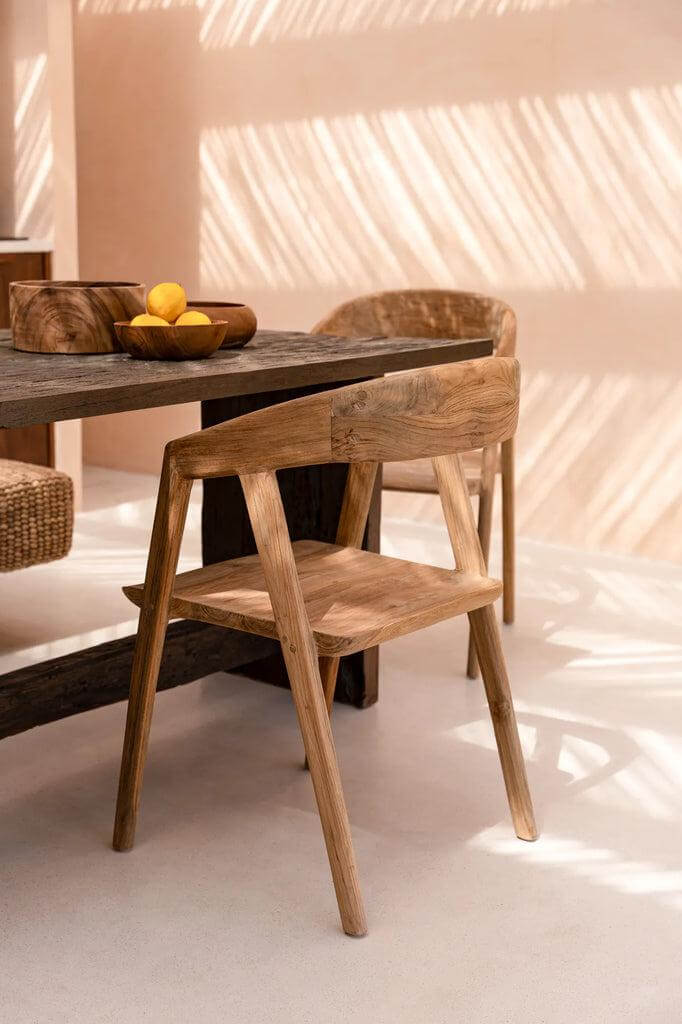 Alt Tag: Elegante Teluk eetkamerstoel van hergebruikt teakhout bij houten eettafel in zonnige eetkamer, tijdloos ontwerp.