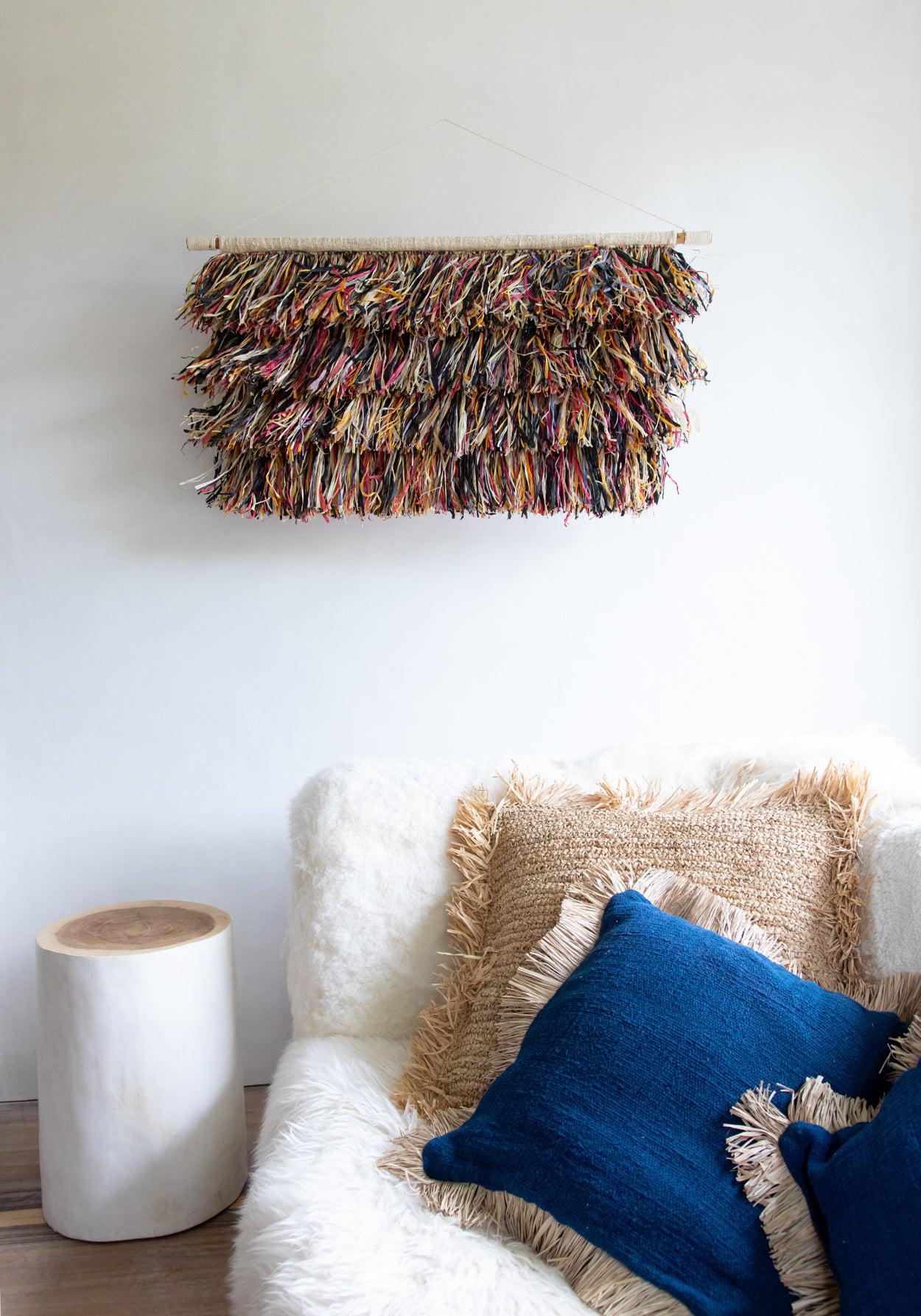 Gezellige woonkamer met De Tribe Kruk - Naturel Wit naast een pluizige bank en kleurrijke wanddecoratie.