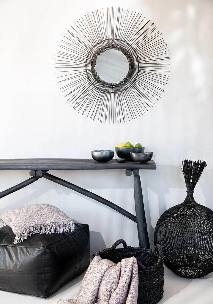 Op de jaren 70 geïnspireerde zwarte tropische spiegel van rotan hangt in een modern interieur met natuurlijke decoratie.