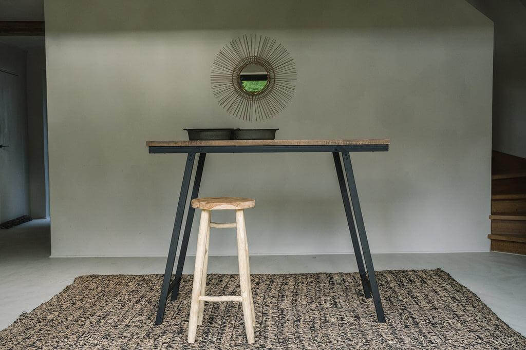 De Tropical Spiegel in zwart rotan, jaren 70 design, op muur met tafel en kruk. Perfecte toevoeging voor interieur met natuurlijke tinten.
