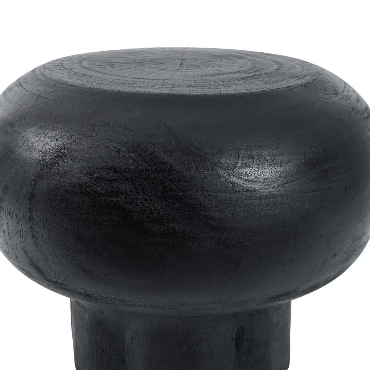 Close-up view of the black De Tutup Coffee Table's suar wood surface, showcasing its smooth, rounded Bohemian design.