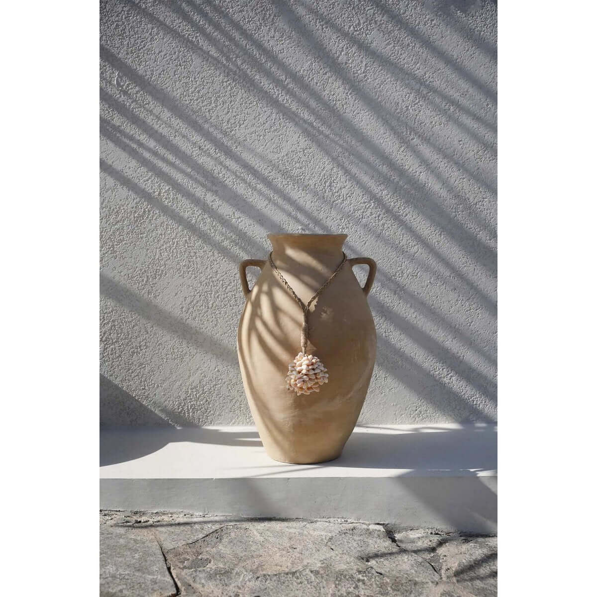 Bohemian De Vanilla Shell Tassel on decorative vase, handmade from shells by Balinese artisans, adding exotic charm to home decor.