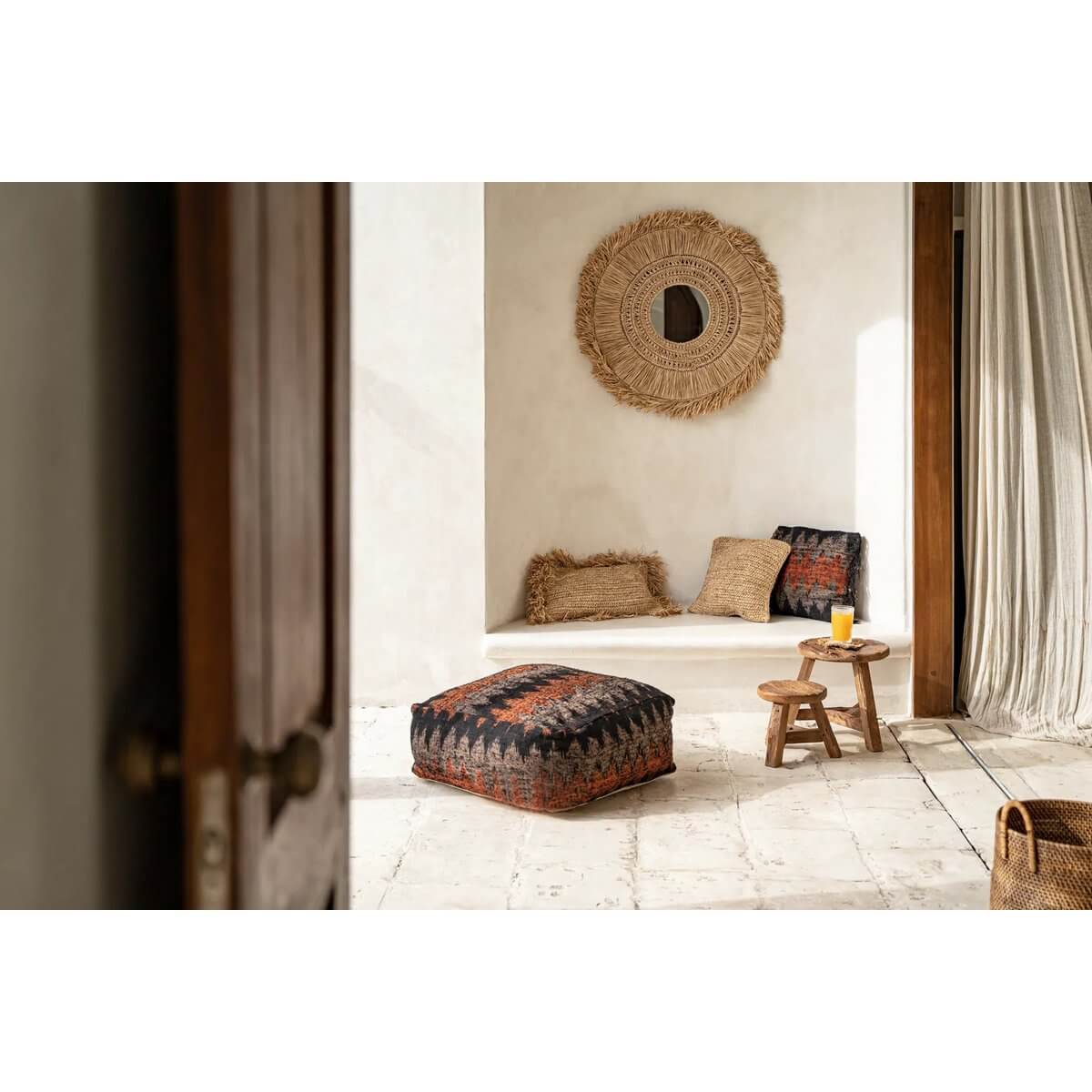 Woonkamer met Yuki-spiegel aan de muur, natuurlijke raffia-designs en warme tinten voor een serene kustsfeer.