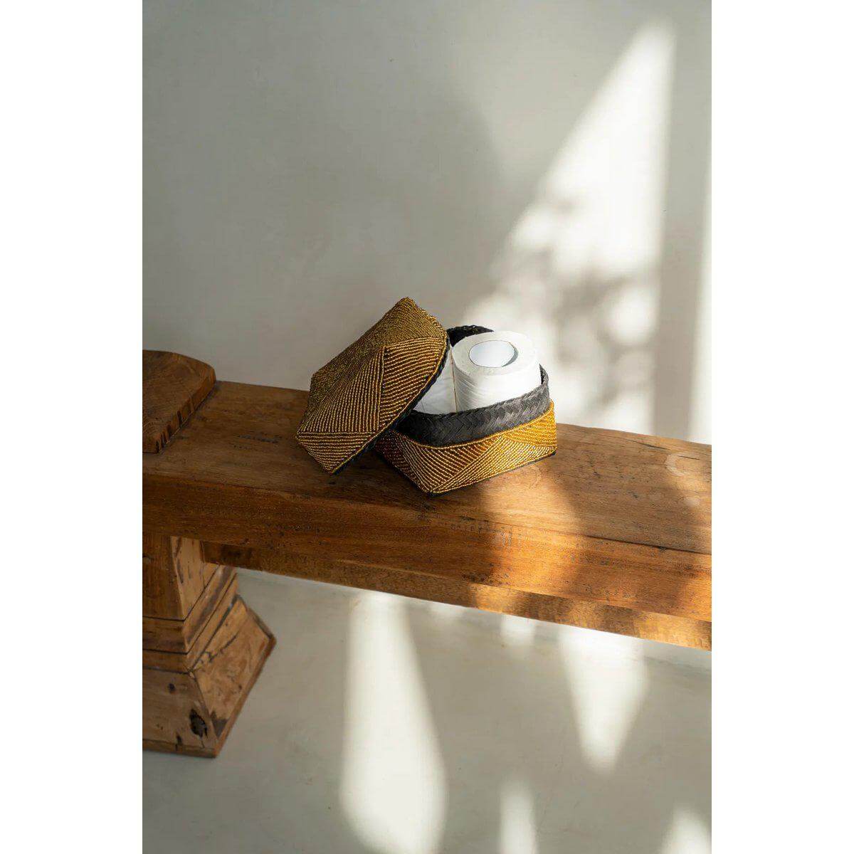 Handgemaakte gouden kralenmand uit Bali op houten tafel, ideaal als opberger of decoratief element. Uniek ambachtelijk cadeau.