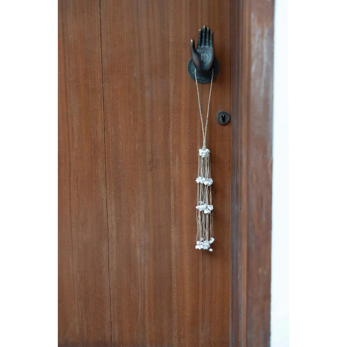 Handmade white shell tassel hanger by Balinese artisans, adding a bohemian touch to doors and walls. From Bazar Bizar Living.