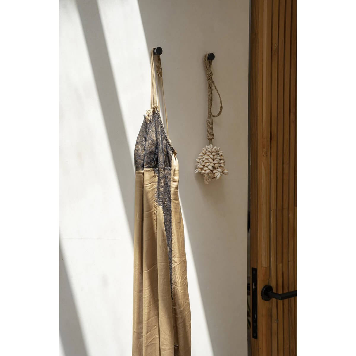 Rustic wall decor with a seashell tassel and hanging robe, adding a bohemian touch to a minimalistic interior.