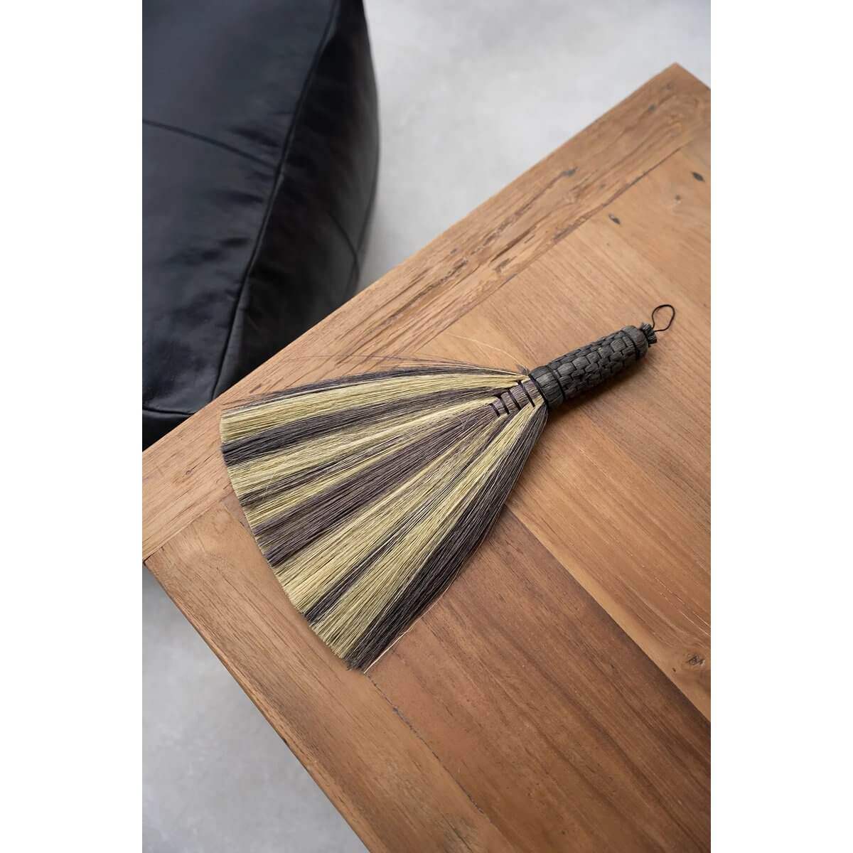 Bohemian black natural Indonesian broom on wooden table, perfect for a stylish, decorative touch in indoor and outdoor spaces.