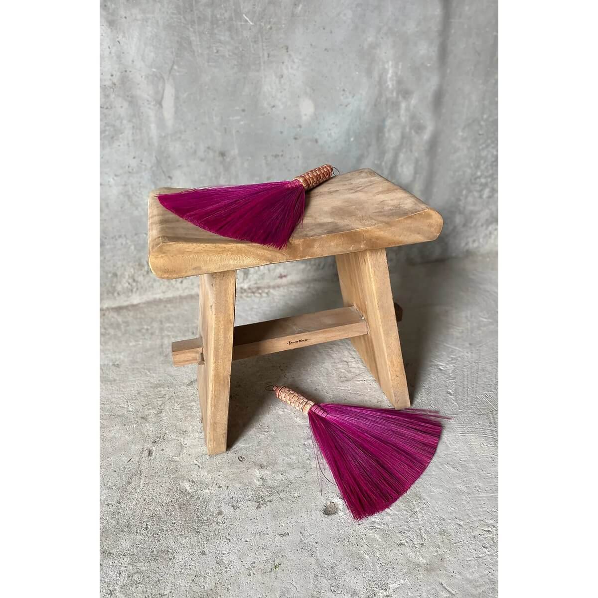 Bohemian pink hand brooms on a wooden stool, perfect for chic interiors or covered outdoor spaces, bringing a touch of Indonesia.