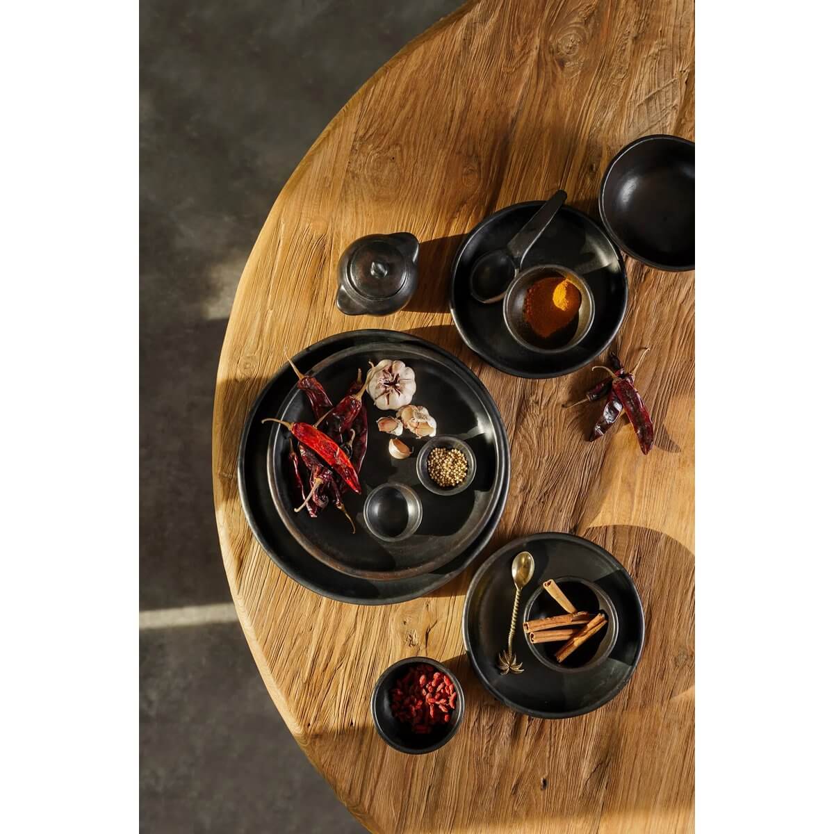 Bohemian black-burnt pottery on wooden table with spices; perfect for stylish food presentation and unique kitchen decor.