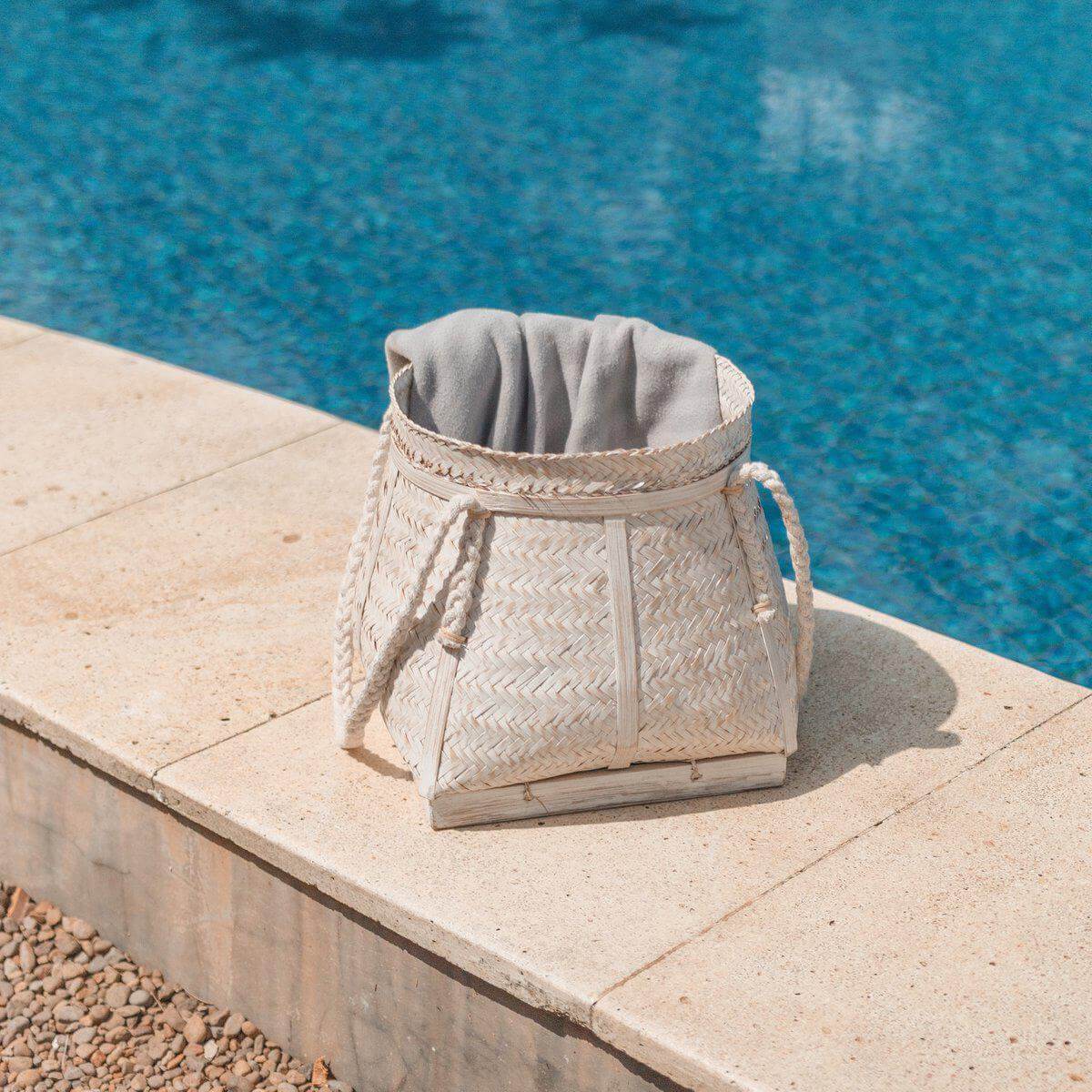 Boho bamboe opbergmand bij zwembad, ideaal als wasmand of plantenhouder. Handgemaakt, duurzaam en plasticvrij. Gratis verzending bij €350+.
