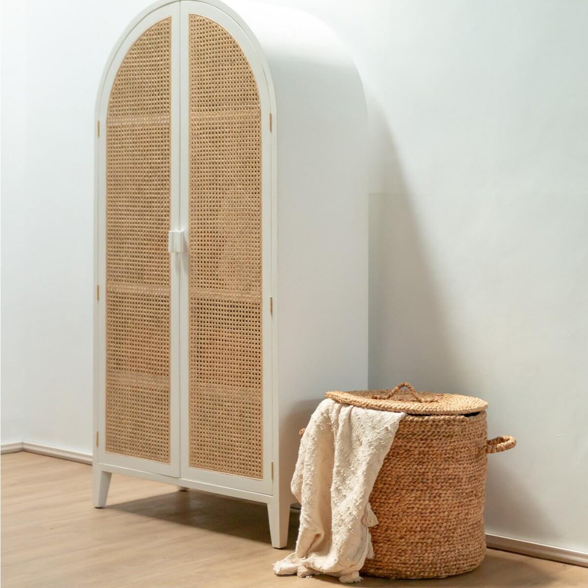 Grote Wasmand met deksel AMAN, gemaakt van waterhyacint, handgeweven mand naast kast in neutraal interieur.