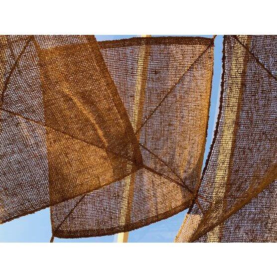 Bohemian coco fence made of natural coconut fibers providing rustic elegance and privacy against a clear blue sky.