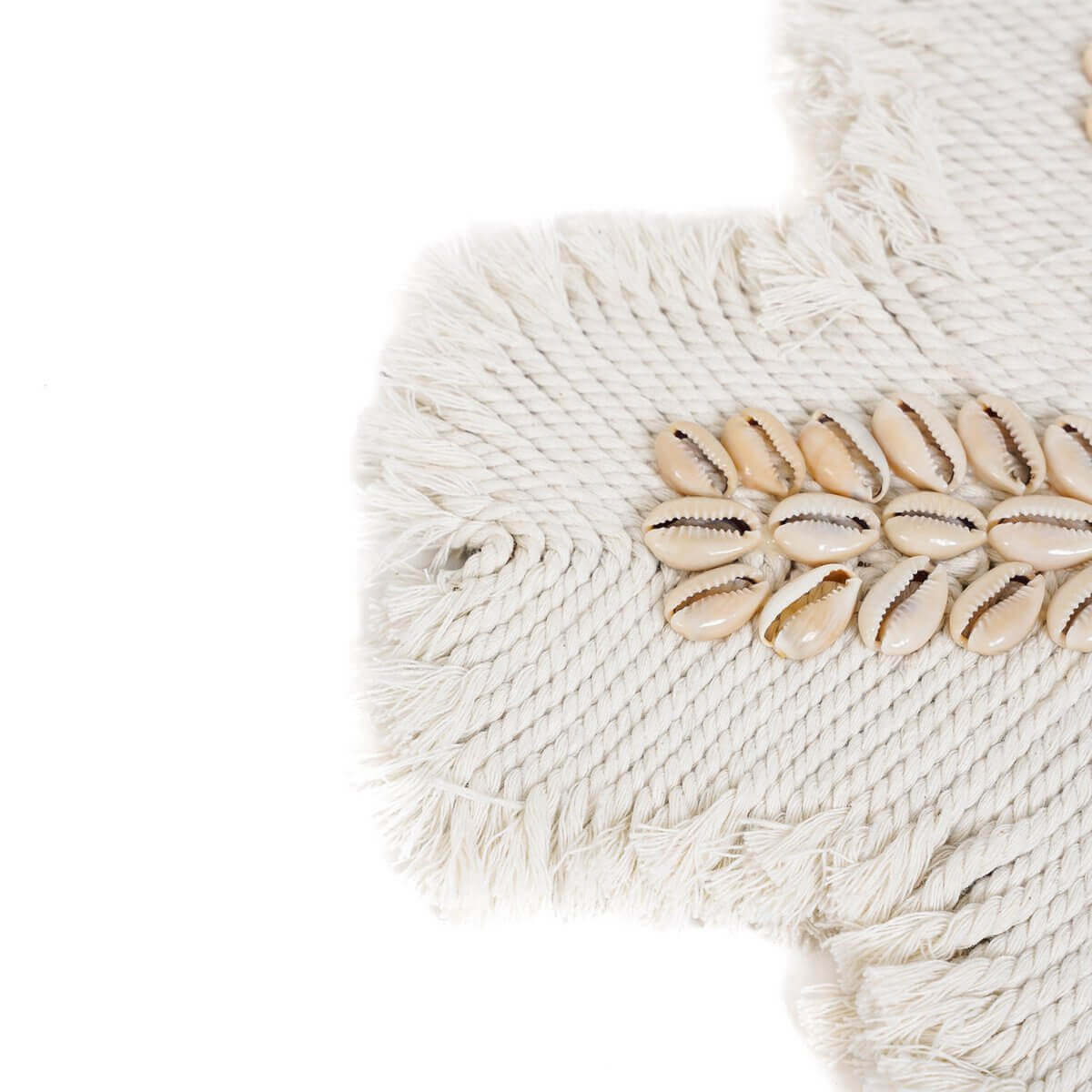 Gedetailleerde close-up van een wit macrame-kruis met kaurischelpen, ontworpen voor wanddecoratie en een kustsfeer.