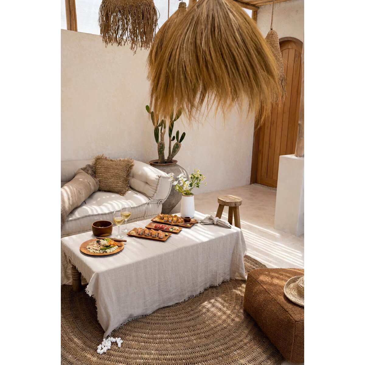 Gezellige woonkamer ingericht met beige linnen tafelkleed op eettafel, servies en decoratieve verlichting.