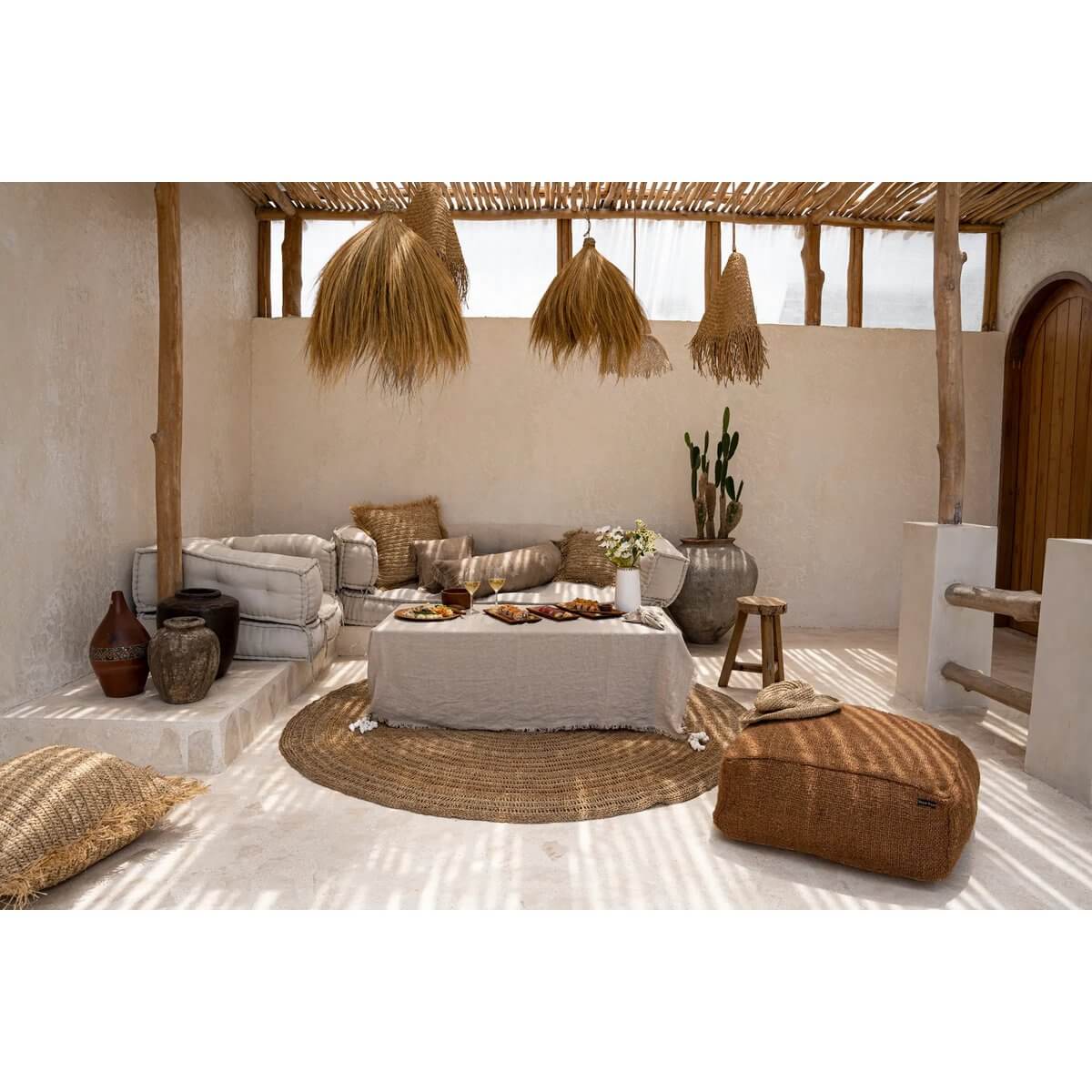 Breezy boho woonkamer met natuurlijke decoratieve elementen en rieten lampen, witte sofa en poef, voor een relaxte sfeer.