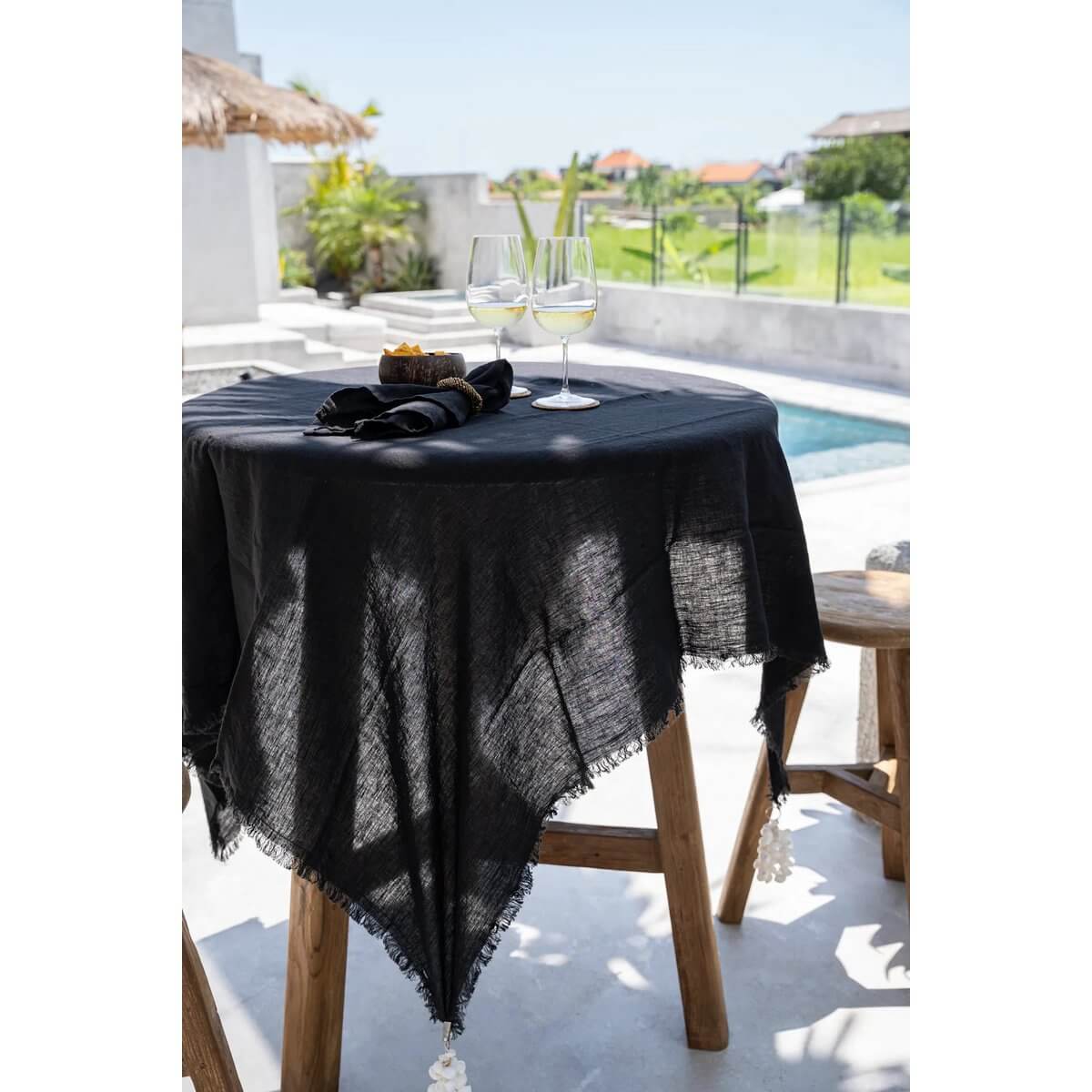 Zwart linnen tafelkleed 150x200 op moderne buitentafel met wijnglazen, perfect voor stijlvolle eetsetups.